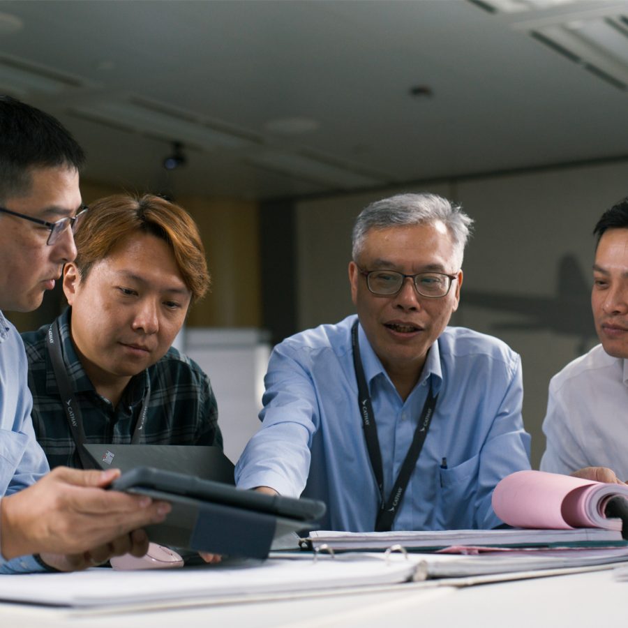 Four men in smart shirts review log reports.